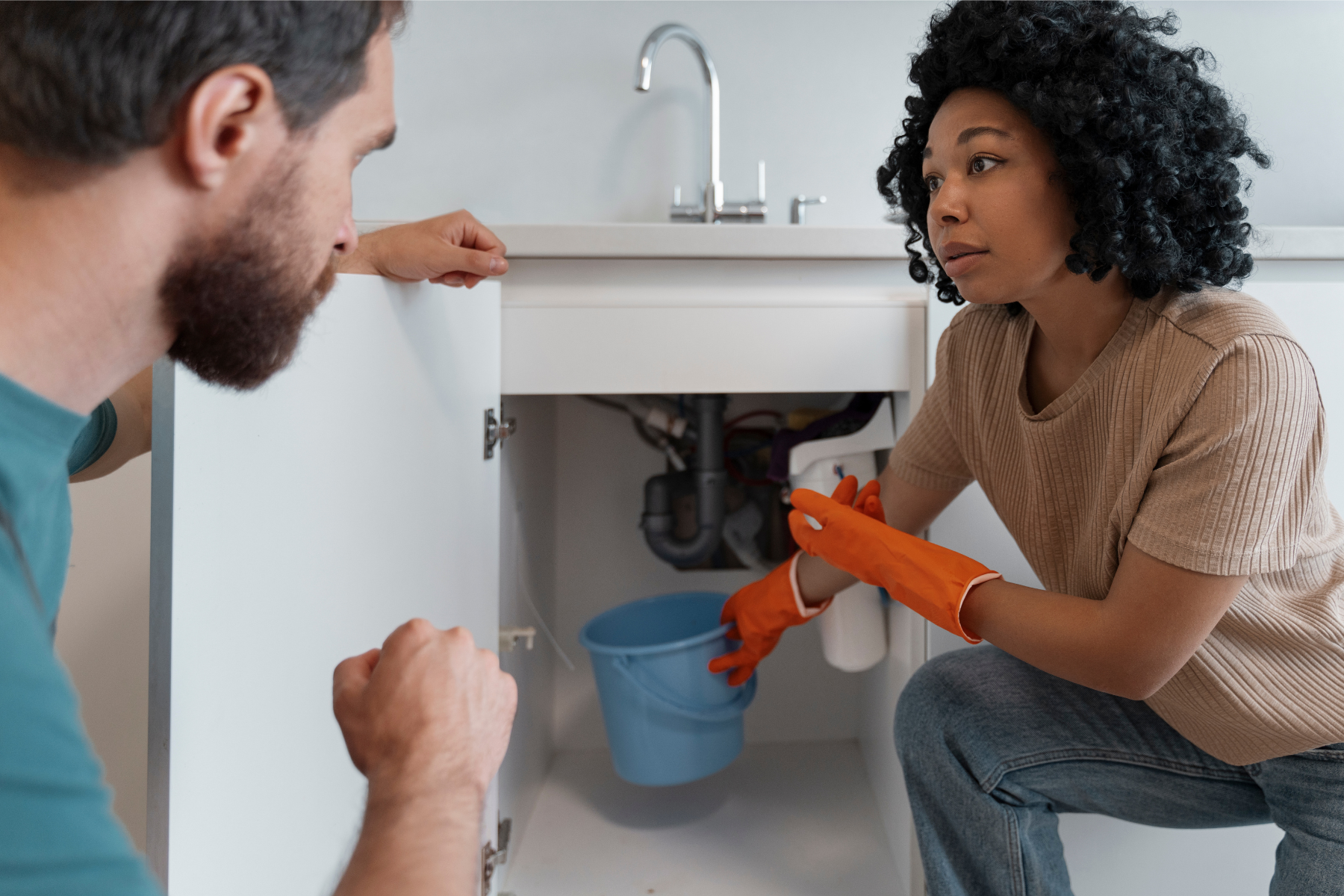Plumber and customer looking at a burst pipe under a sink